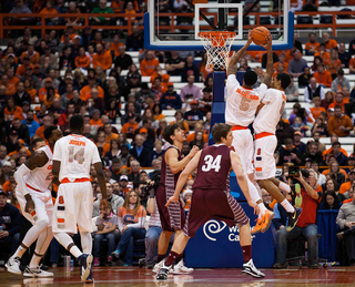 Forward Chris McCullough skies for the ball as he bumps into Gbinije with two Colgate players watching.