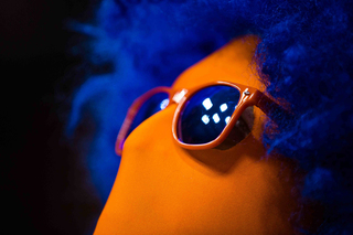 ESF graduate Dylan Lyon, dressed in an orange jumpsuit, blue afro and orange and blue sunglasses, looks on in the Carrier Dome on Tuesday night.