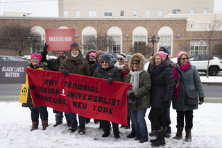 Protesters hold a banner of Syracuse's May Memorial Unitarian Universalist Society, one of several community groups that supported Saturday's march. 